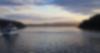 A yacht watches a cloudy sunrise over a blue, calm bay